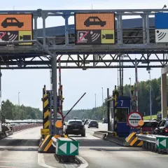 Bramki autostradowe A4 z wyświetlaczami informacyjnymi i szlabanami, w tle samochody.