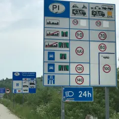 Znaki drogowe informujące o różnych rodzajach dróg, opłatach i ograniczeniach prędkości. Wskazują na różne rodzaje pojazdów i dopuszczalne prędkości na poszczególnych odcinkach.