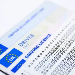 Dwa brytyjskie prawa jazdy i wydruk z danymi.