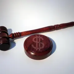Młotek sędziowski i drewniany krążek z symbolem dolara.