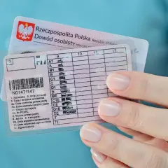 Dłoń trzyma polskie prawo jazdy i dowód osobisty. Zastanawiasz się, ile się czeka na prawo jazdy? Dokument zawiera kategorie pojazdów.