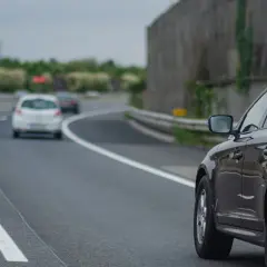 Ciemny samochód na autostradzie, wyprzedzający inne pojazdy.