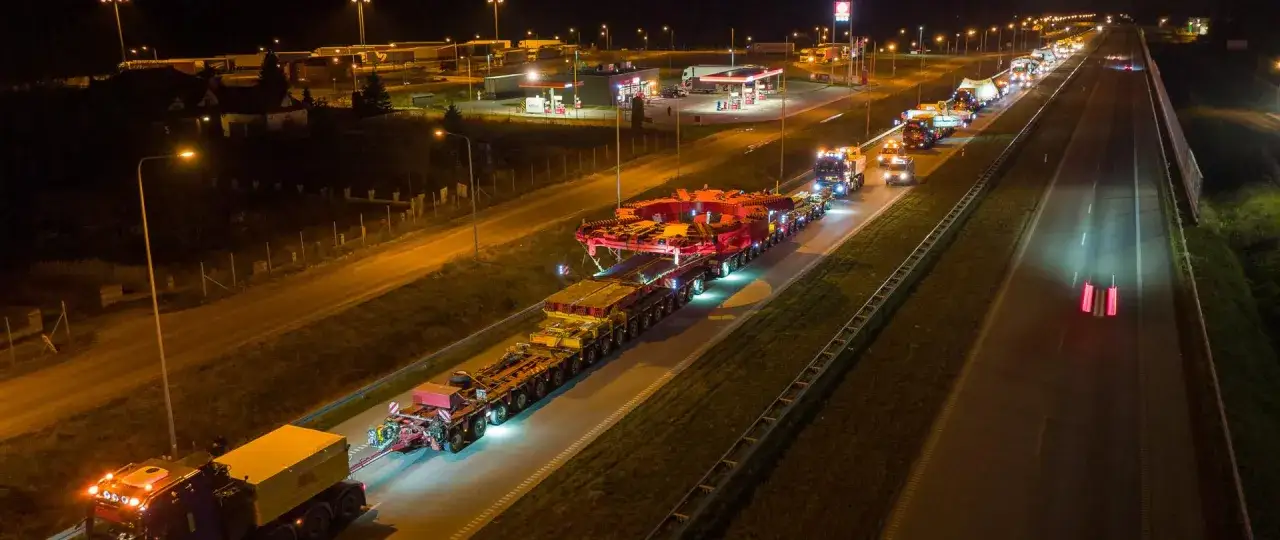 Nocny transport wielkogabarytowego ładunku, który jest pojazdem nienormatywnym, na autostradzie.