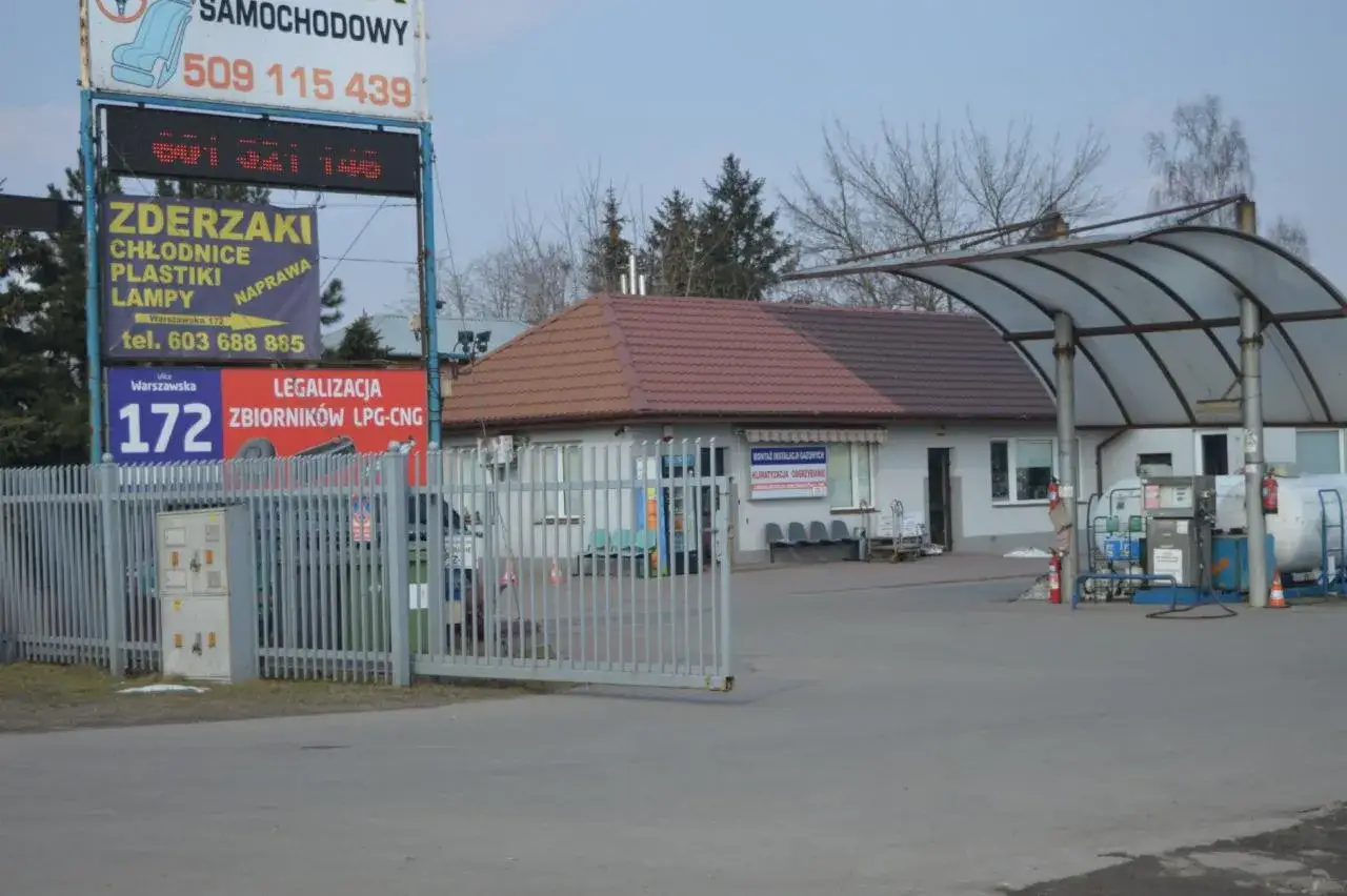 Warszawa, ul. Warszawska 172. Znak informuje, ile kosztuje legalizacja butli LPG-CNG. Obok stacja paliw.