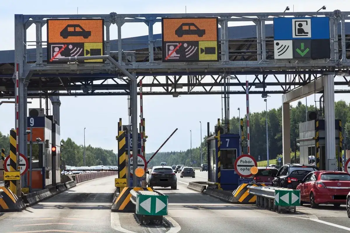 Pobieranie opłat za autostradę A4 Katowice-Kraków. Samochody zbliżają się do bramek, na których wyświetlane są znaki informacyjne.